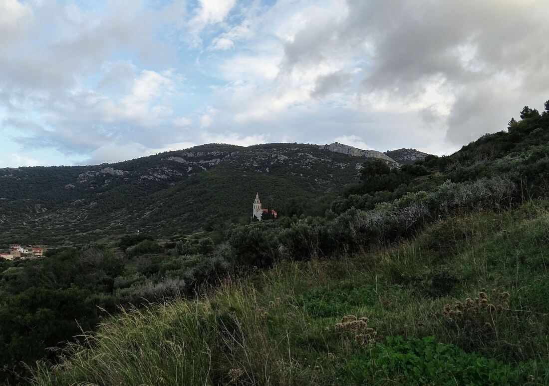 Pogled preko polja na zvonik crkve sv. Nikole iznad Komiže