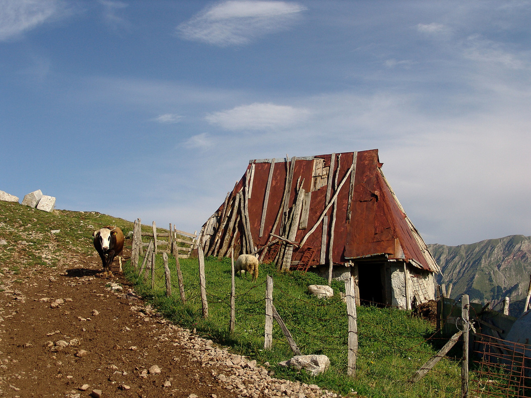 Lukomir. Posljednje kuće na istočnom dijelu sela iznad kanjona rijeke Rakitnice (desno). Lijevo na brijegu vidi se manja nekropola stećaka. U pozadini desno planina Visočica
