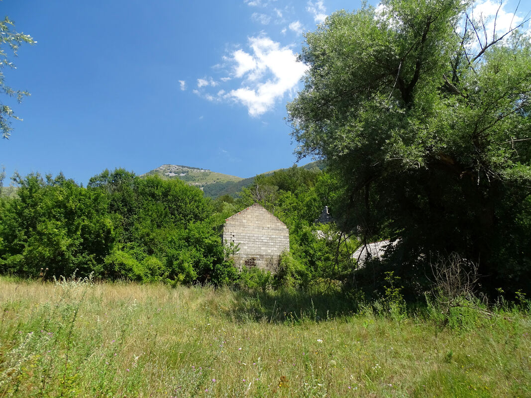 Ruševne kuće nekadašnjeg sela Dabašnice. Vrh Stražbenica u pozadini