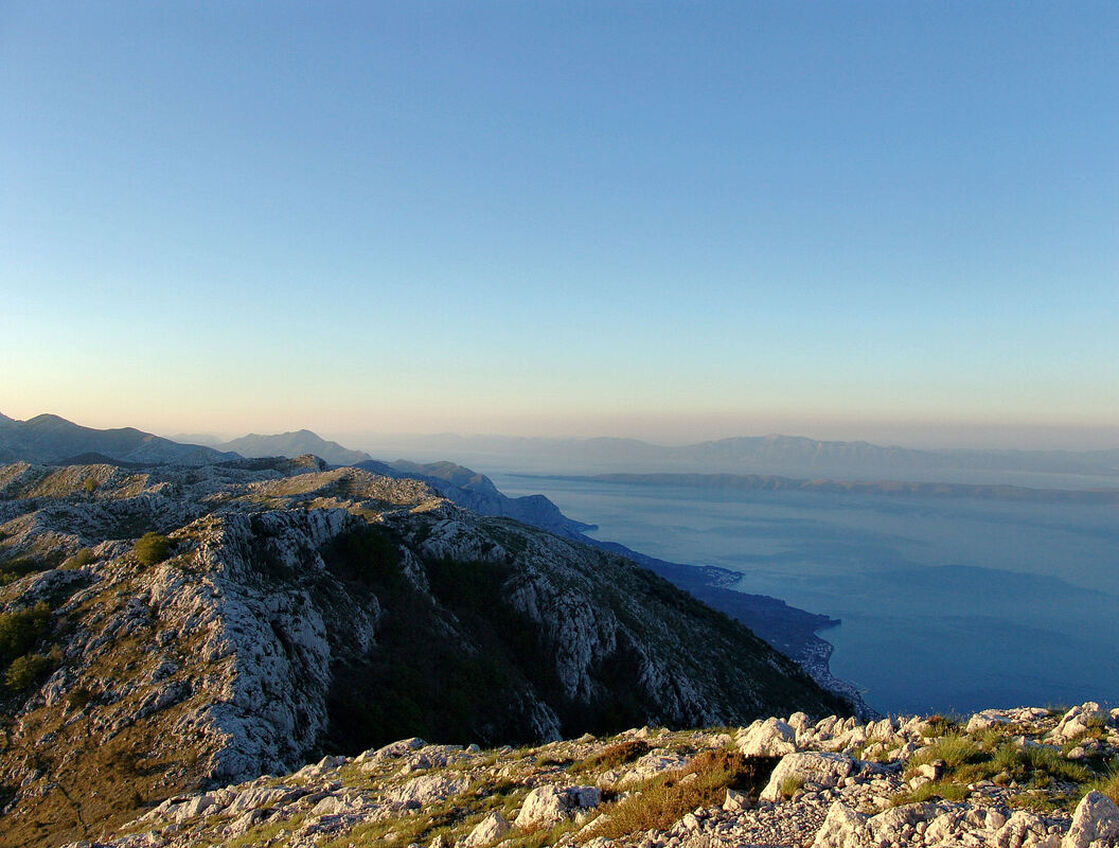 Pogled na obalu Makarskog primorja, južno od Makarske. Pogled s vrha Vošac u smjeru juga. U sredini fotografije vidi se izduženi niski istočni dio otoka Hvara, a na horizontu su Pelješac (u sredini) i Korčula (desno)