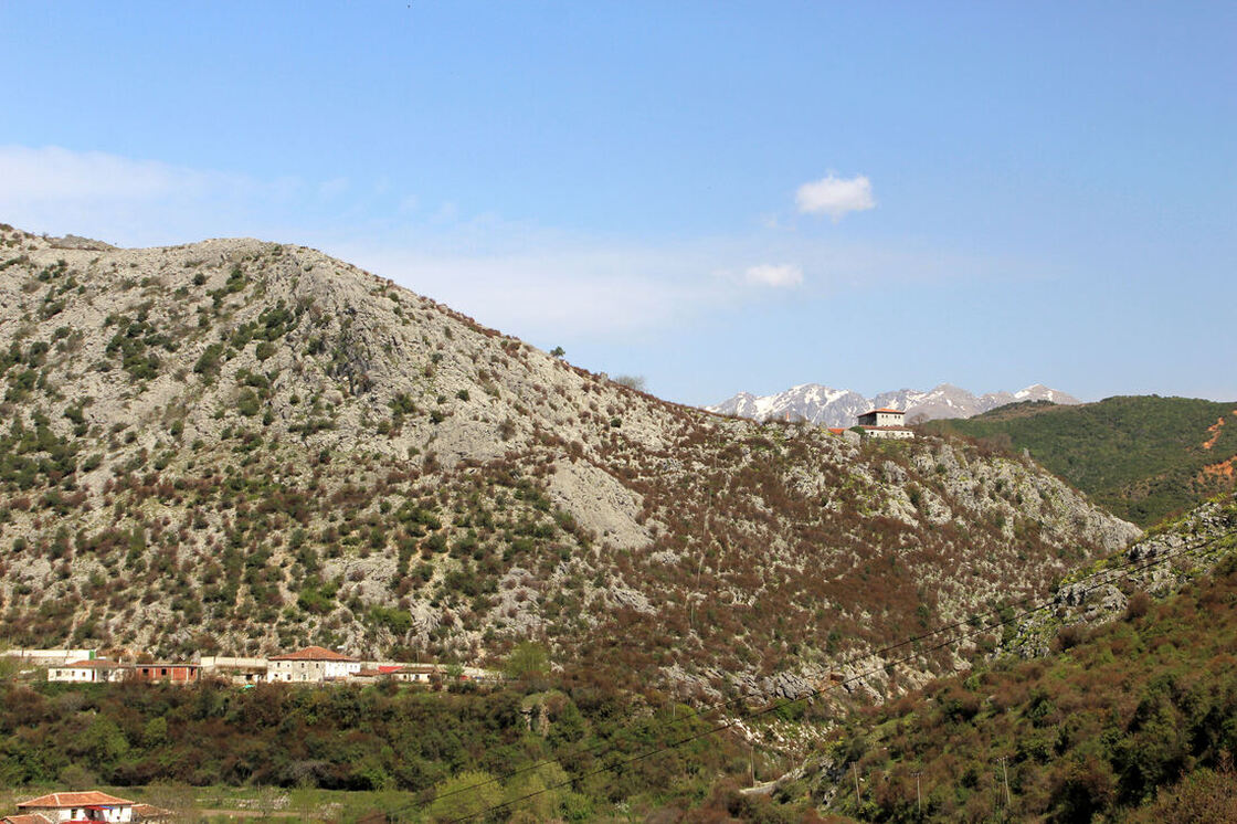 Pogled na jugozapadni dio brda Drisht. U pozadini se vide najviši vrhovi masiva Cukali s ostacima snijega u proljeće.
