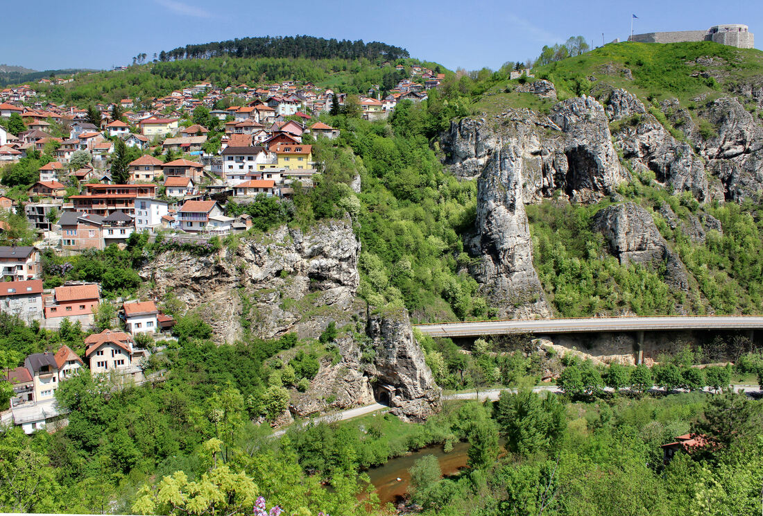 Dijelovi naselja Vratnik (lijevo) i Bijela tapija (desno, gore) na Pašinom brdu, dižu se okomito nad kanjonom Miljacke, gdje se među stijenama ističe soliterni stup Babinog zuba na Darivi.