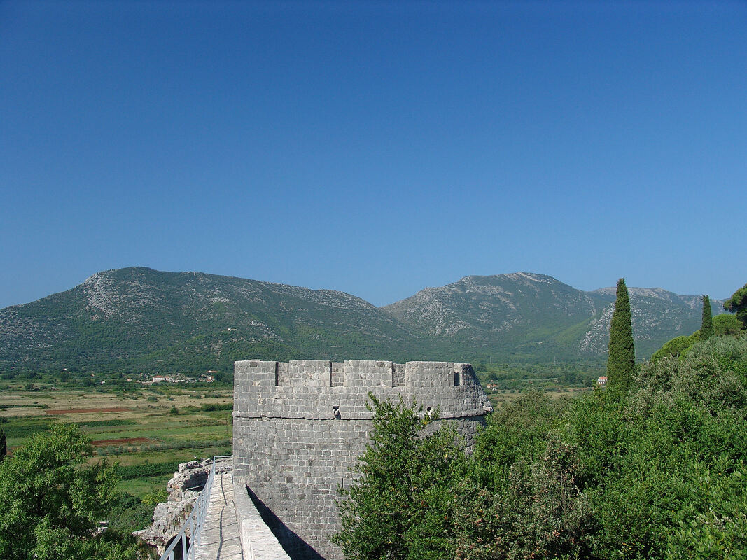 Pogled sa stonskih zidina (kula Minčeta) na brda koja se dižu s jugozapadne strane Stonskog polja. U pozadini se nižu vrhovi (s lijeva nadesno) Stari grad (335 m), i kote 469 i 493 m na Ilijinom brdu.