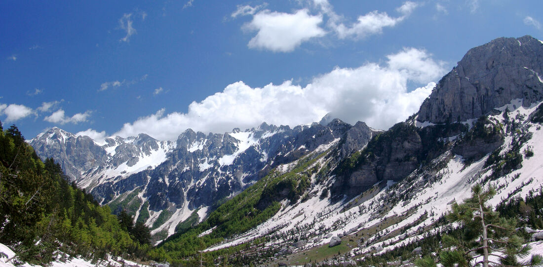 Izvorišna čelenka Valbone ... smještena između padina masiva Popluks (u prednjem planu), i asiva Krasnićkih planina ( u pozadini) koje su povezane grebenom na kojemu se nalazi prijevoj Qafa e Valbonës (desno, iznad čelenke).