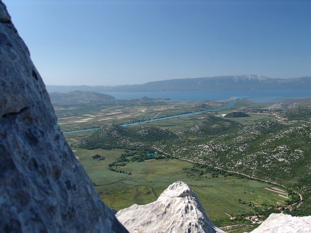 Pogled s Rujnice prema ušću Neretve. U podnožju se vidi Modro oko i zaselak sela Desne. Na horizontu je poluotok Pelješac.