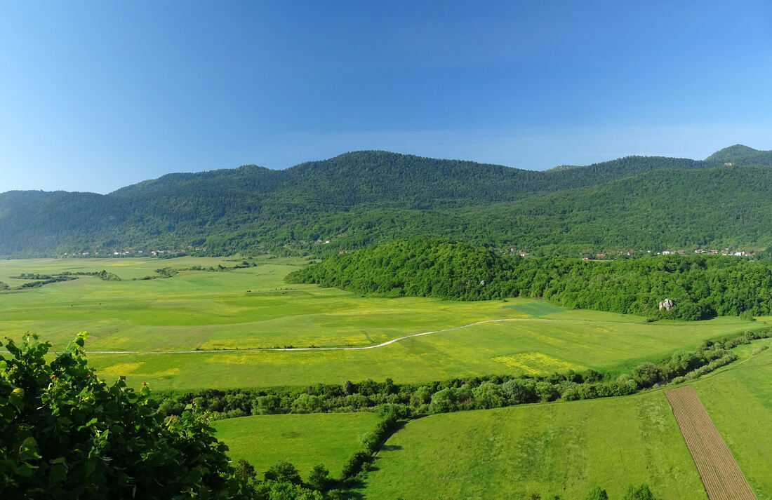 Pogled od Rudinke, preko Kosinjskog polja, na vrhove Velika greda (861 m), desno, i Mačijak (957 m), u sredini